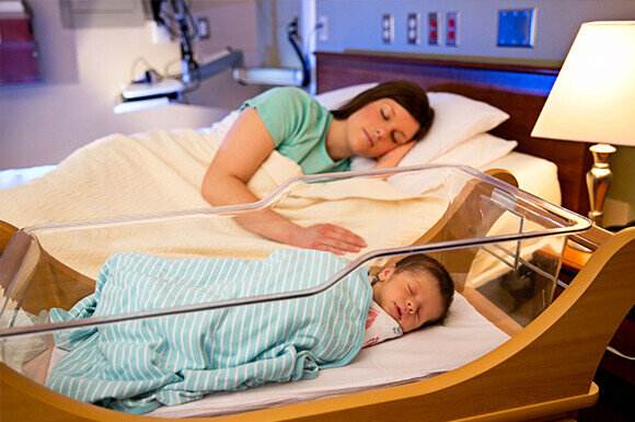 mother with newborn infant asleep next to each other