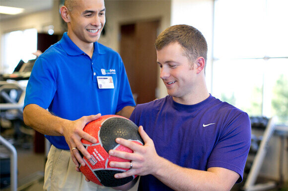 Team Rehab Sports Medicine - Physical Therapist and Patient Using Weighted Medicine Ball